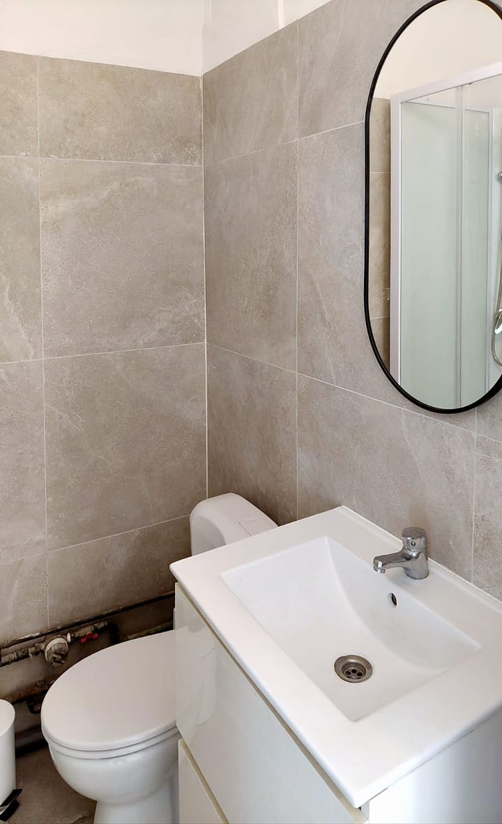 Gerenoveerde badkamer met ronde spiegel, badmeubel en toilet