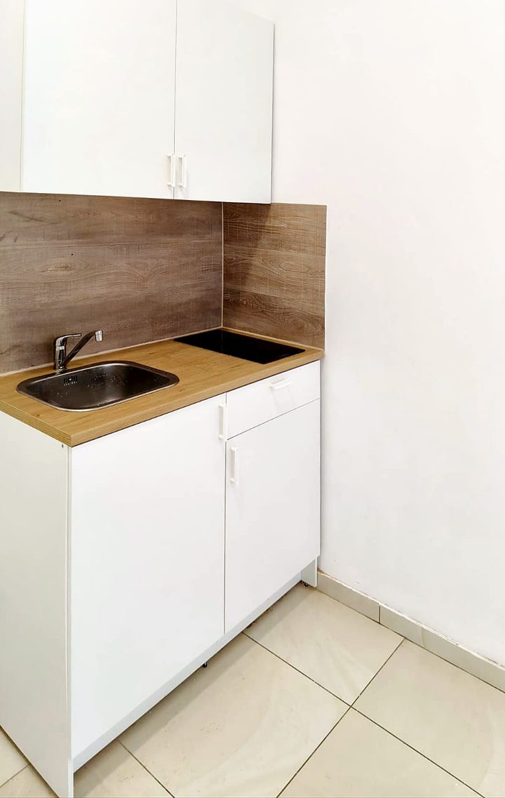 Gerenoveerde compacte witte kitchenette met houten achterwand
