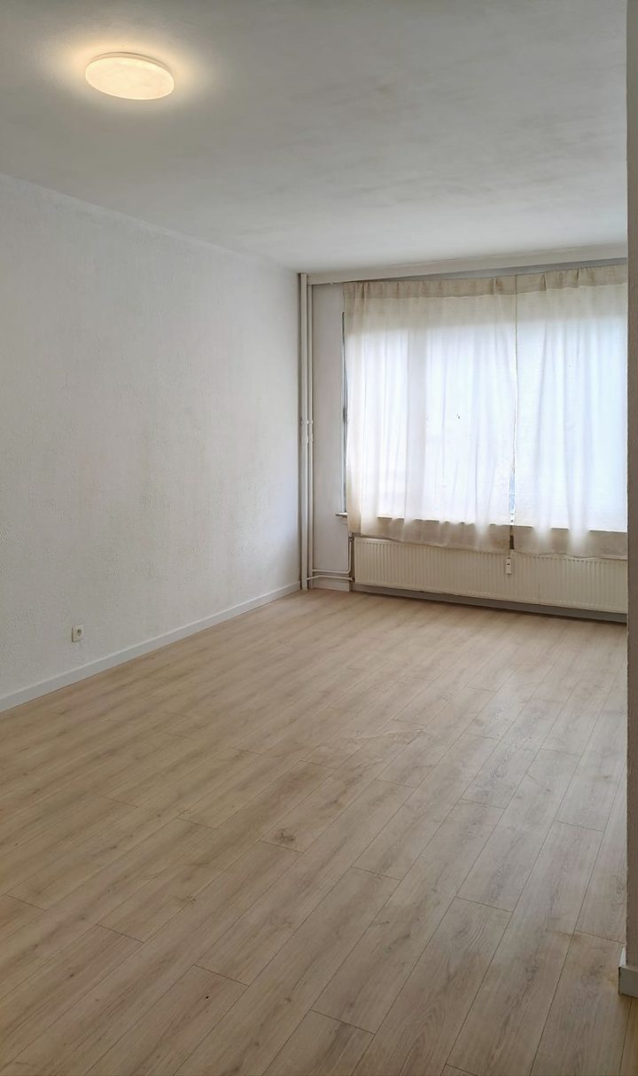 Gerenoveerde woonkamer met laminaatvloer en groot raam